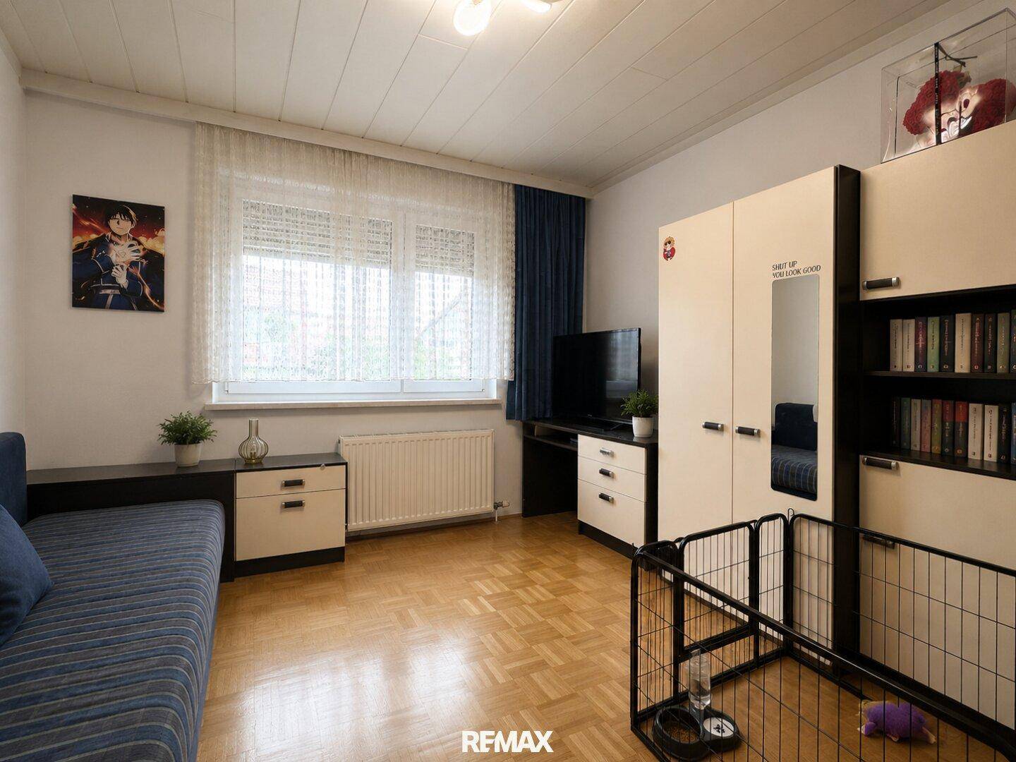 Kinderzimmer oder Gästezimmer mit Parkettboden, Fenster und praktischen Möbeln.
