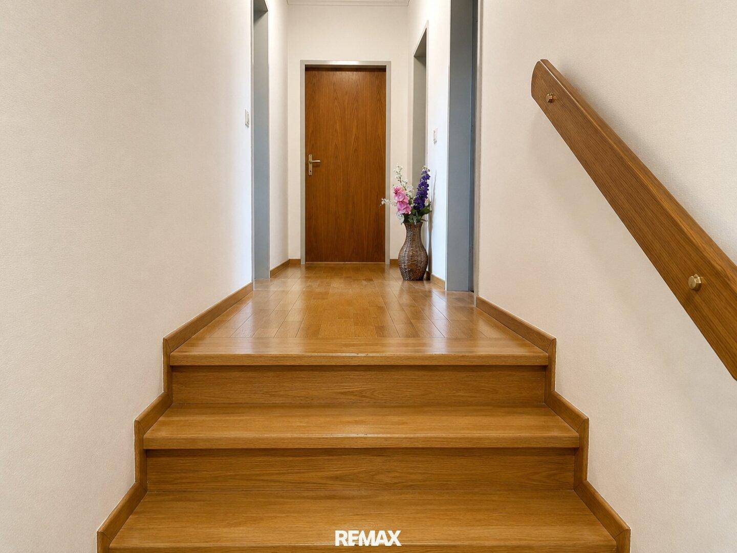 Heller Flur im Obergeschoss mit Holztreppe und Parkettboden.