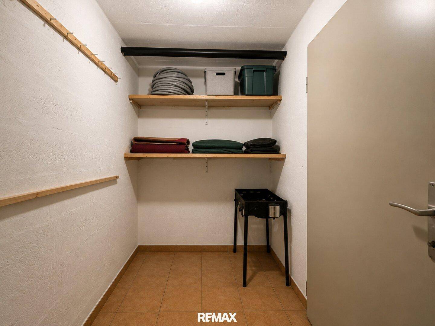 Praktischer Abstellraum mit Regalen und Fliesenboden für zusätzlichen Stauraum.