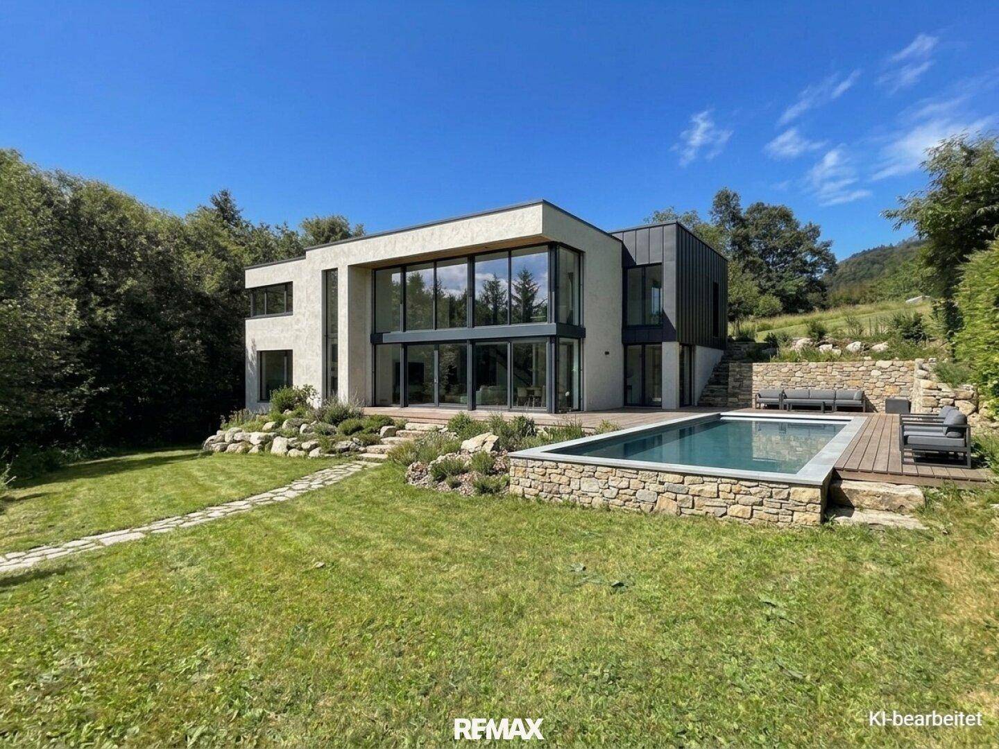 Modernes Haus mit großen Glasfronten, einem Pool und einer gepflegten Gartenanlage unter blauem Himmel.