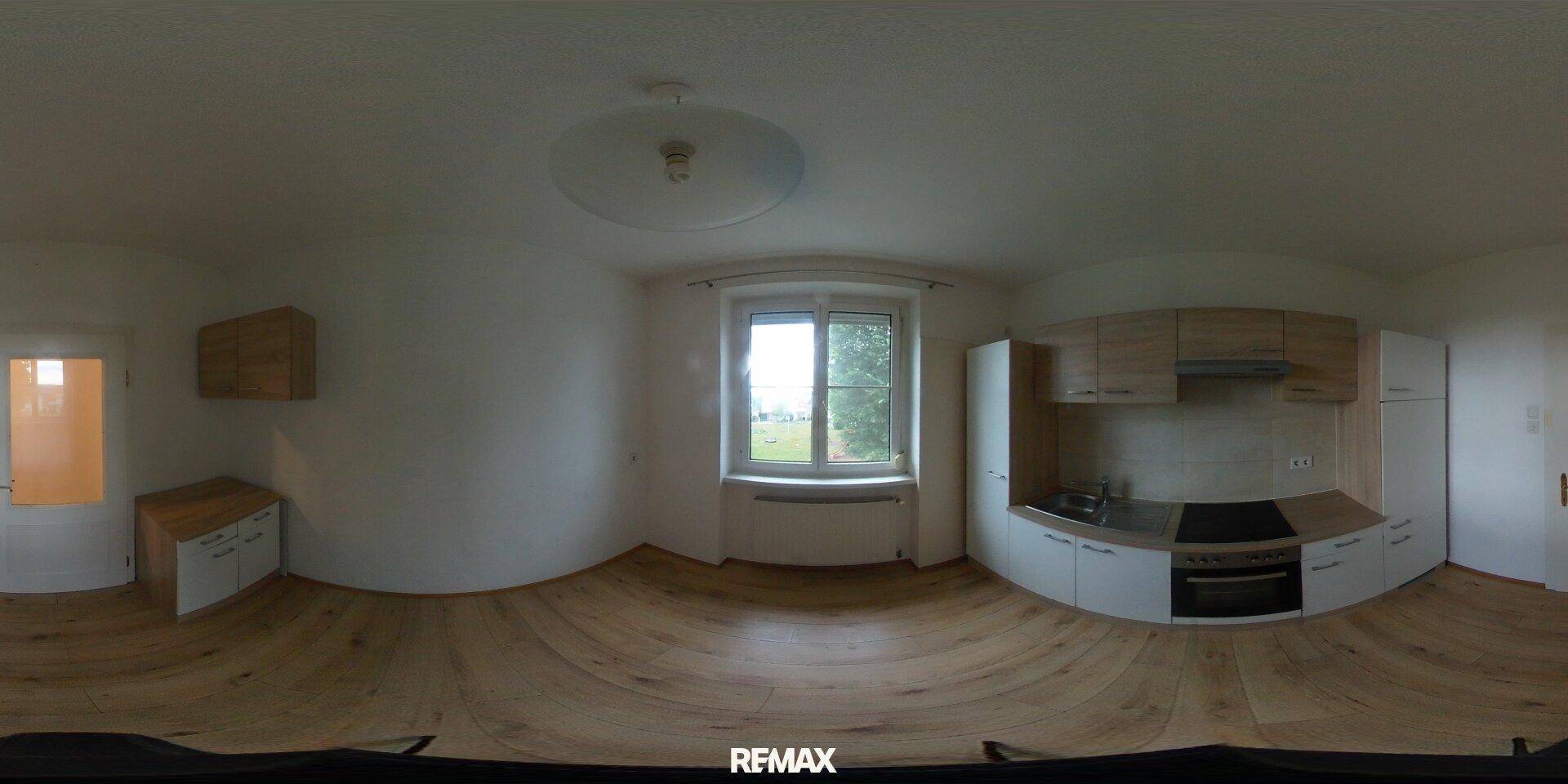 Panoramablick auf die moderne Küche mit hellen Holzfronten und integrierten Geräten.