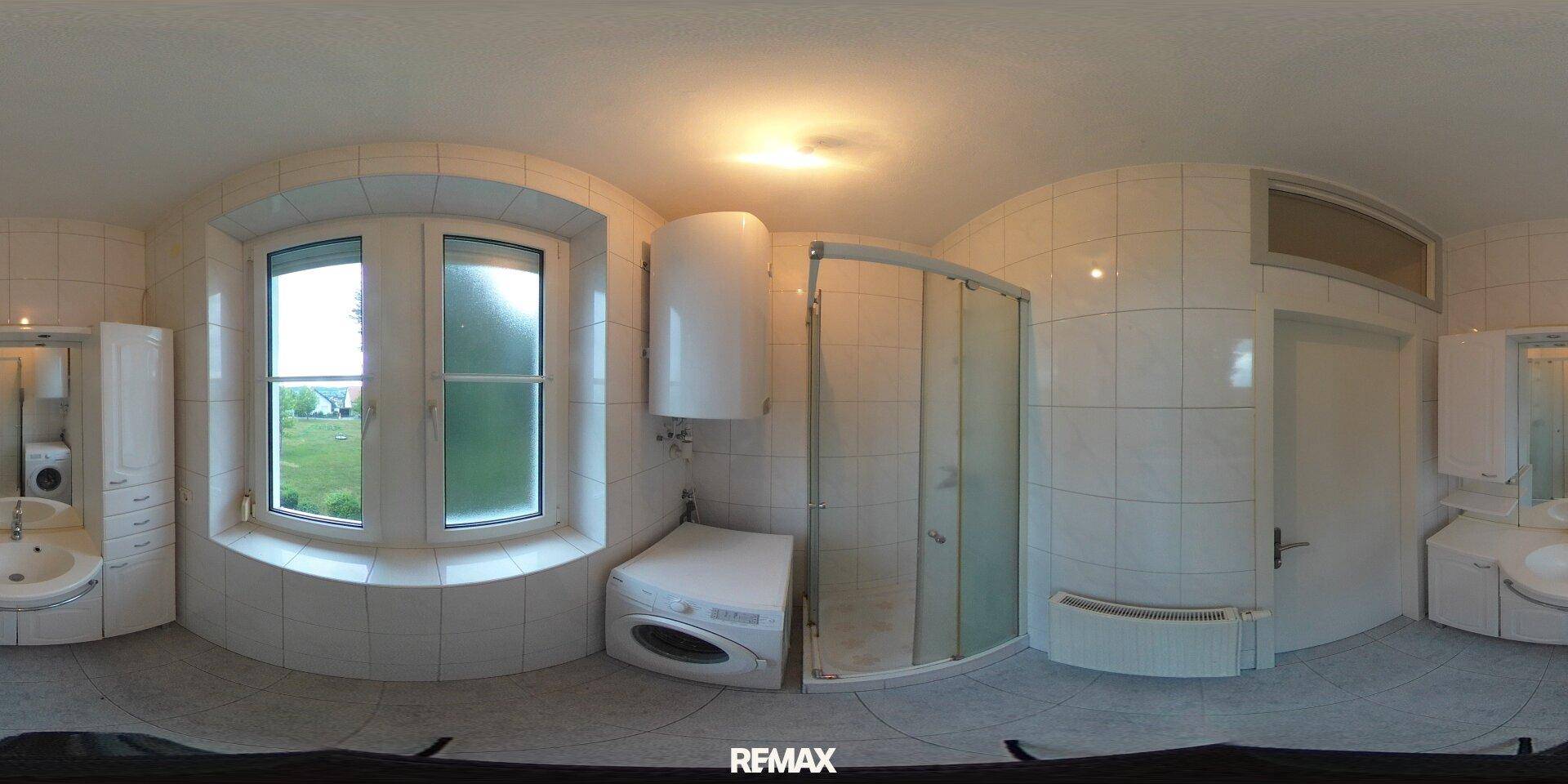 360-Grad-Ansicht des gefliesten Badezimmers mit Dusche, Waschbecken und Waschmaschine.
