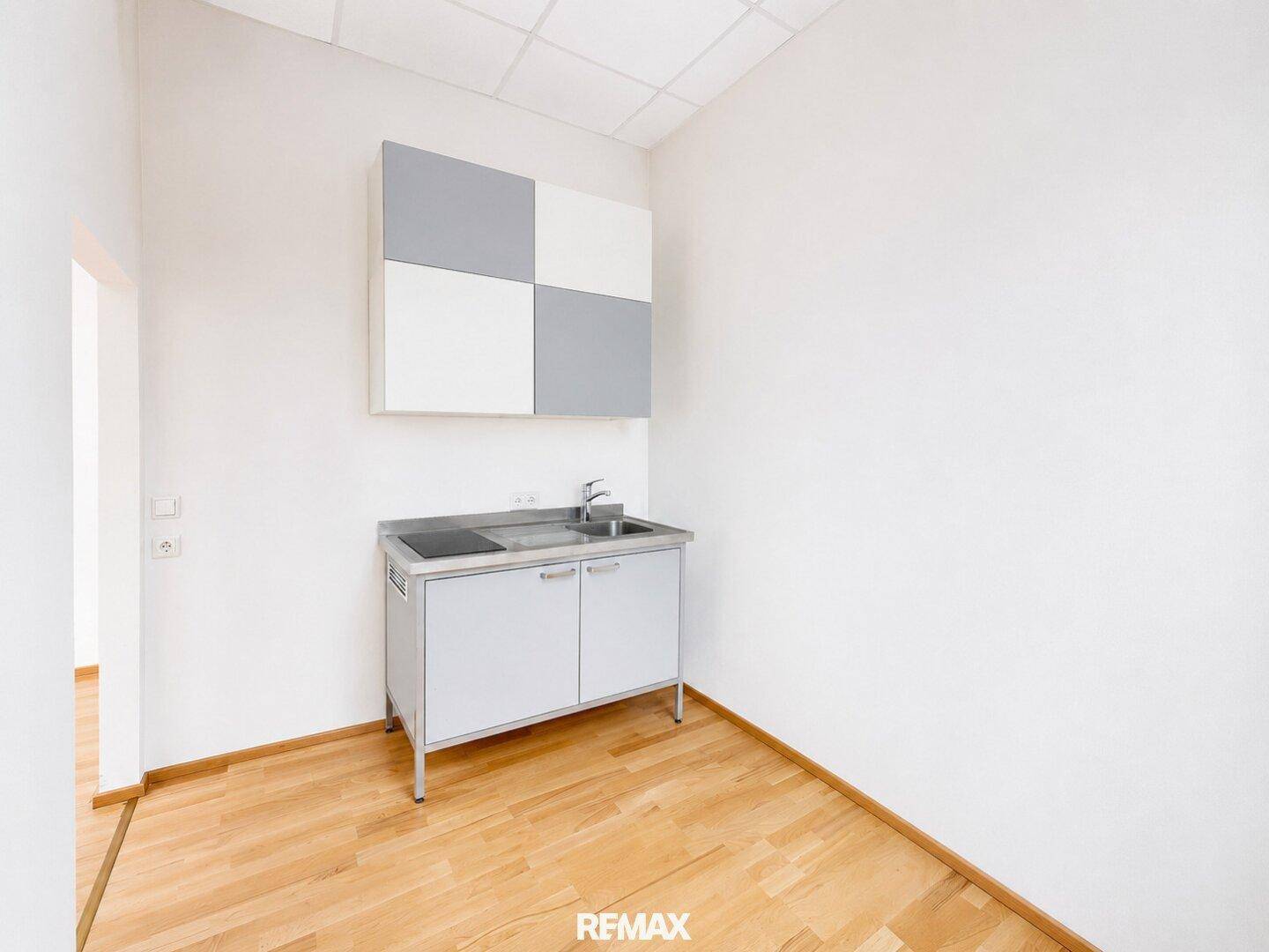 Funktionale Küchenzeile mit Spüle, Kochfeld und Hängeschränken in modernem Design.