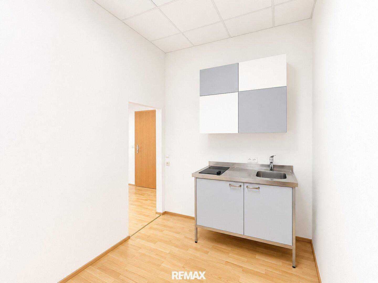 Kleine Küchenzeile mit Spüle und Kochfeld, ideal für eine Büro- oder Apartmentnutzung.