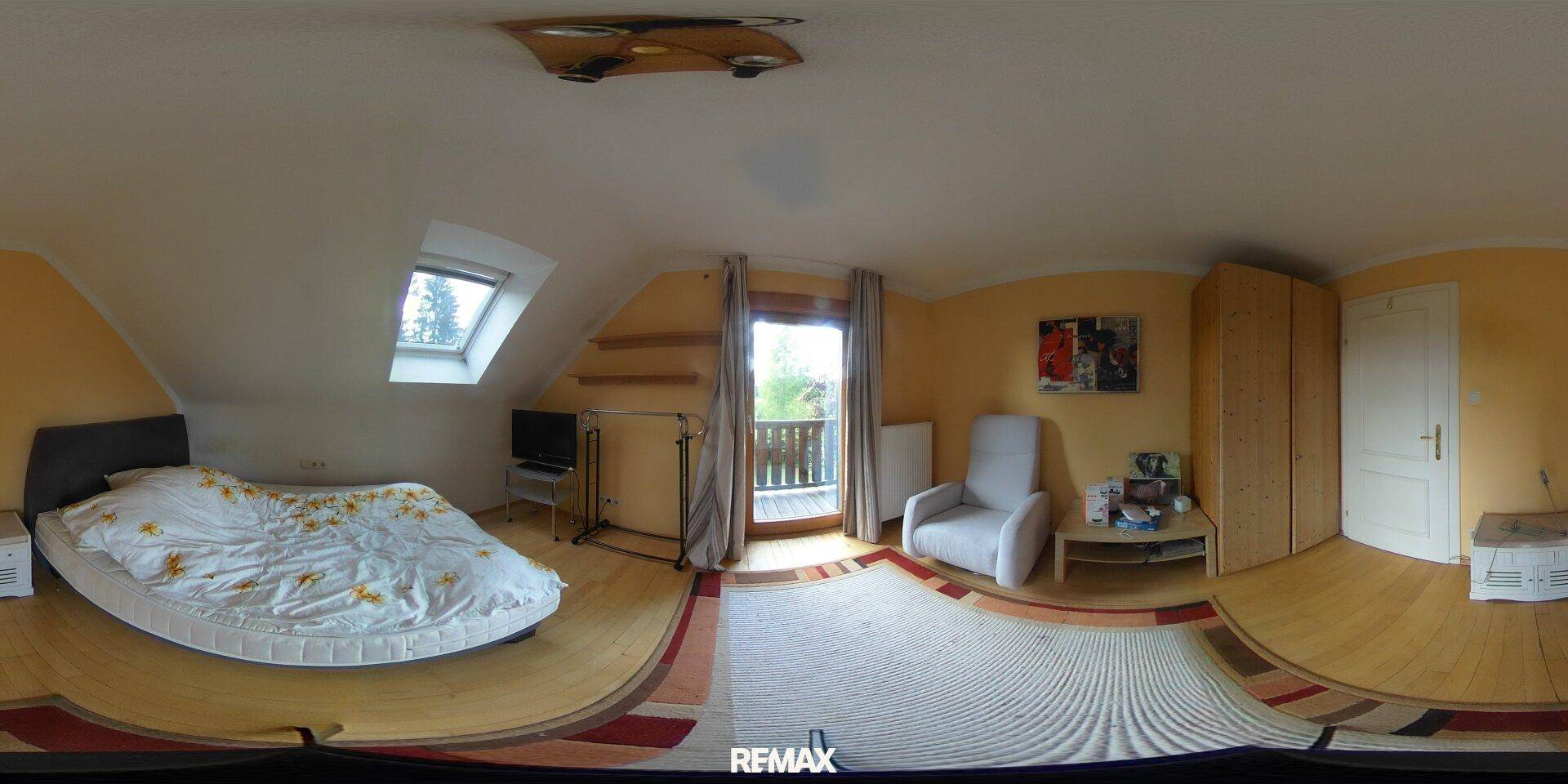 Gemütliches Schlafzimmer mit Holzboden, Dachschräge, Bett und Zugang zu einem kleinen Balkon.