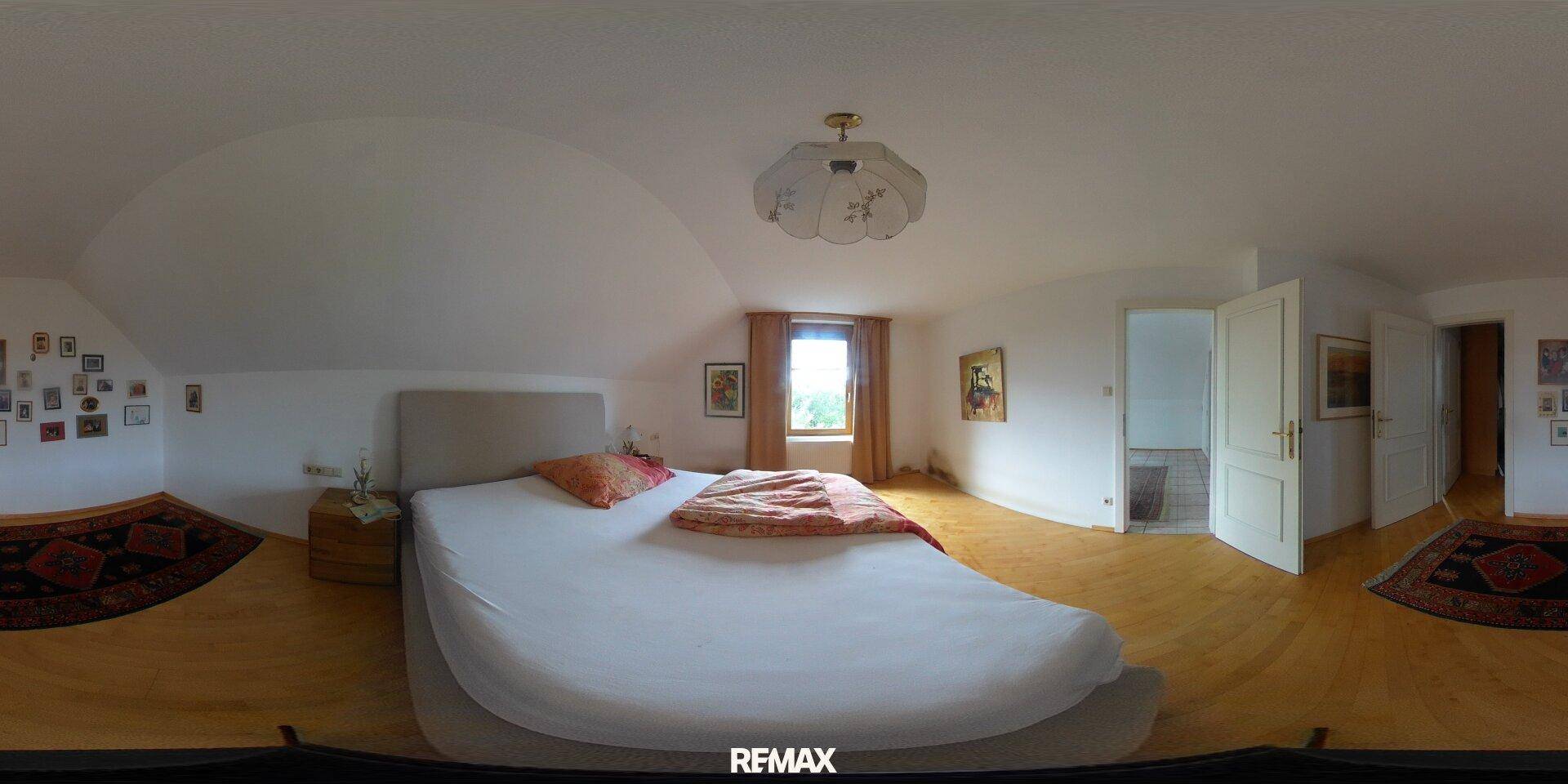 Geräumiges Schlafzimmer mit Holzboden, Dachschräge und einem Fenster für natürliches Licht.