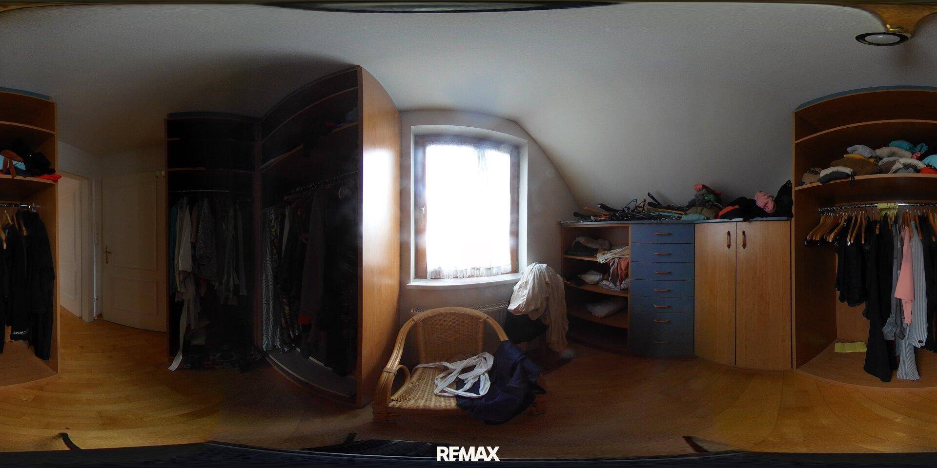 Geräumiger begehbarer Kleiderschrank mit Holzboden und eingebauten Schränken unter der Dachschräge.