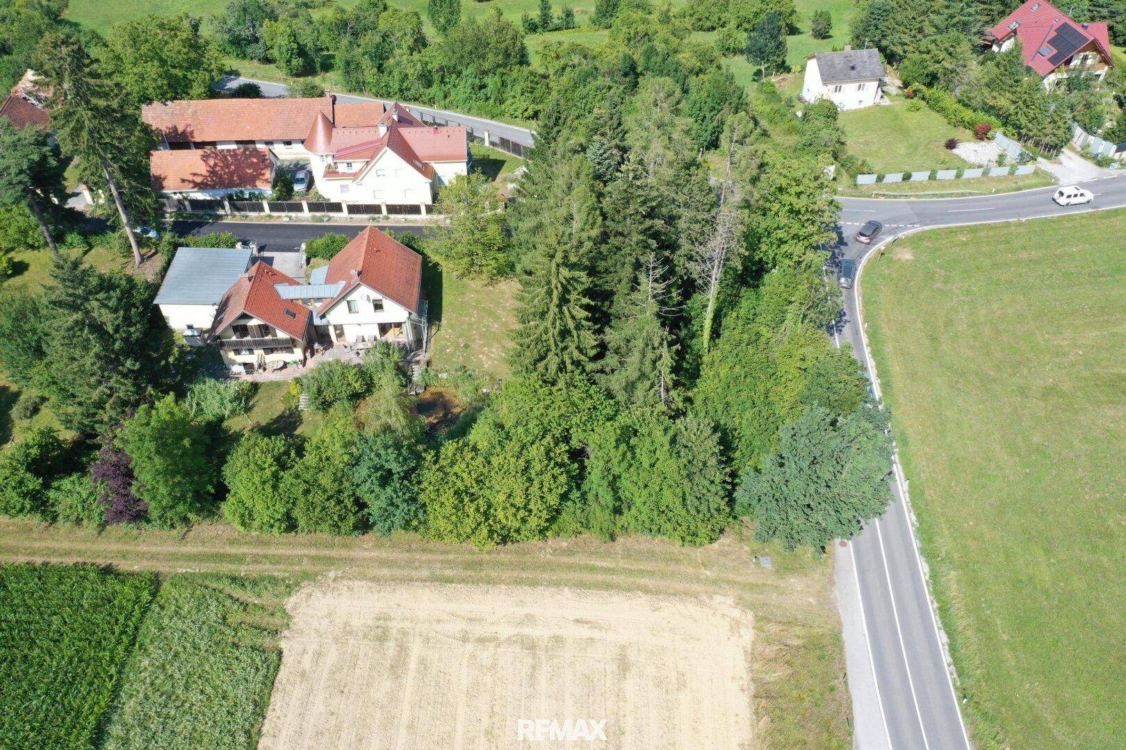 Weitläufige Luftaufnahme mit Wohnhäusern, Feldern, Straßen und üppiger Vegetation in ländlicher Umgebung.