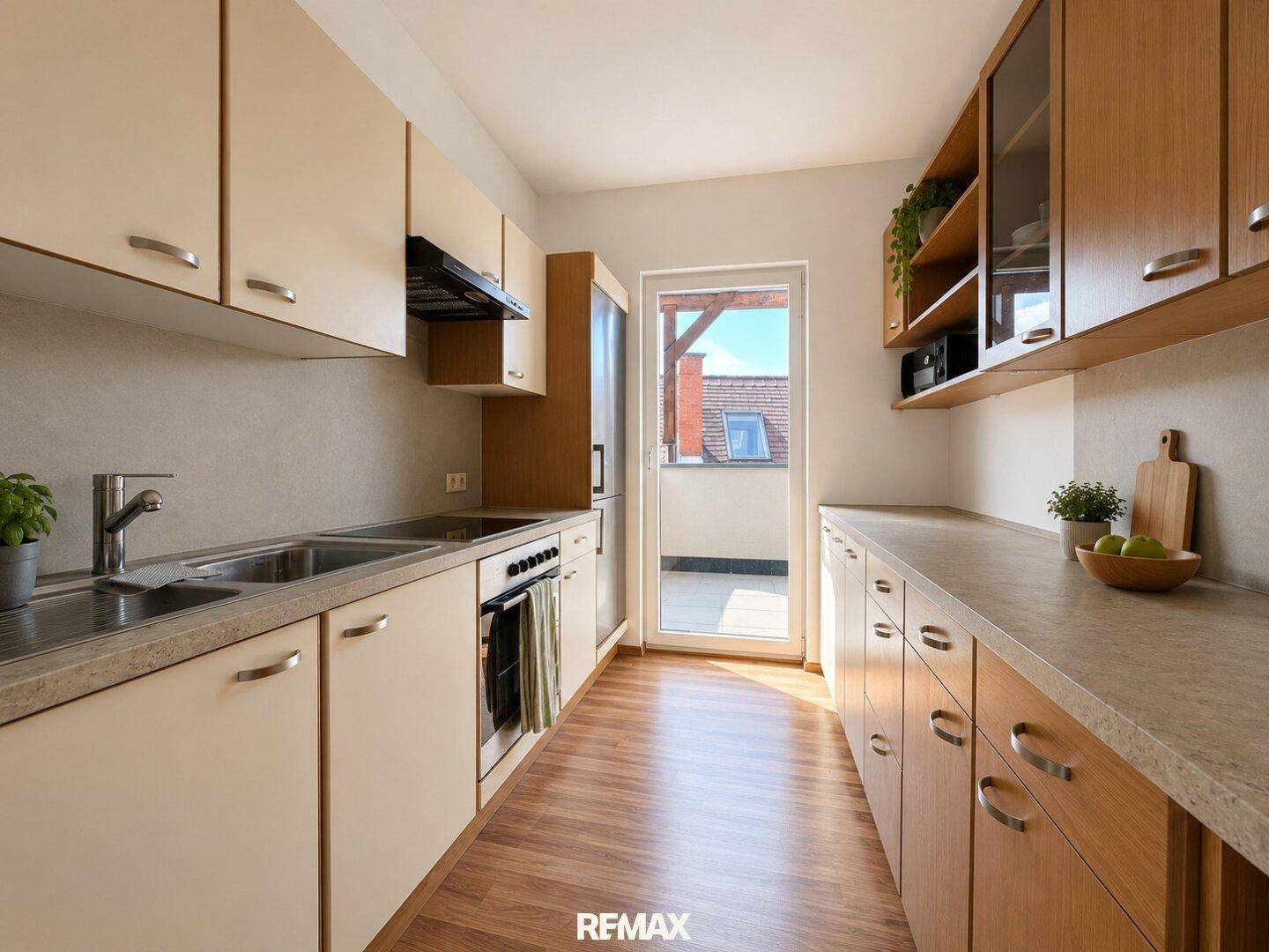 Funktionale Küche mit hellen Schränken, Holzdetails und Zugang zu einem kleinen Balkon.