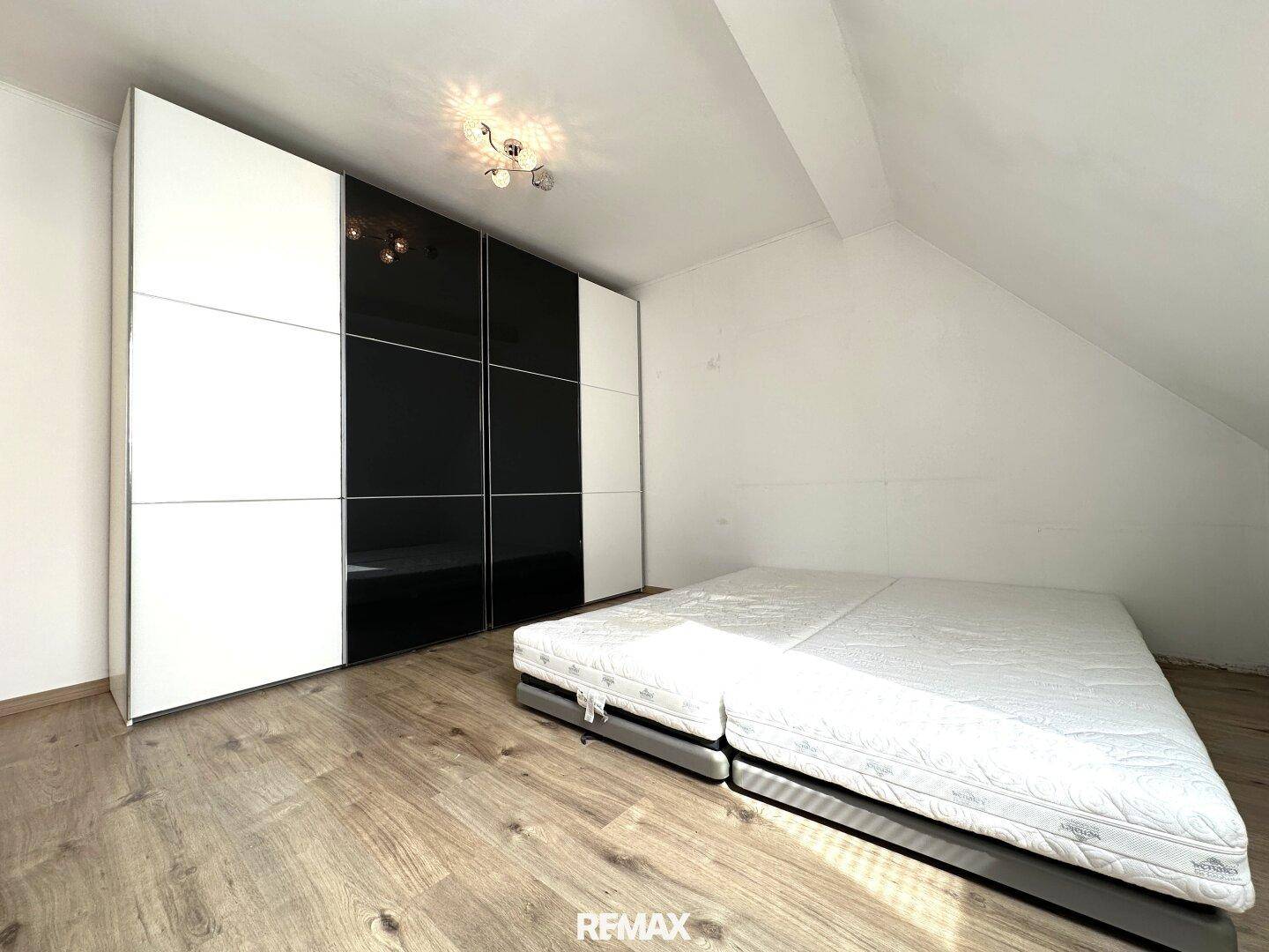 Schlafzimmer mit großem Kleiderschrank und Matratze, unter einer Dachschräge gelegen.