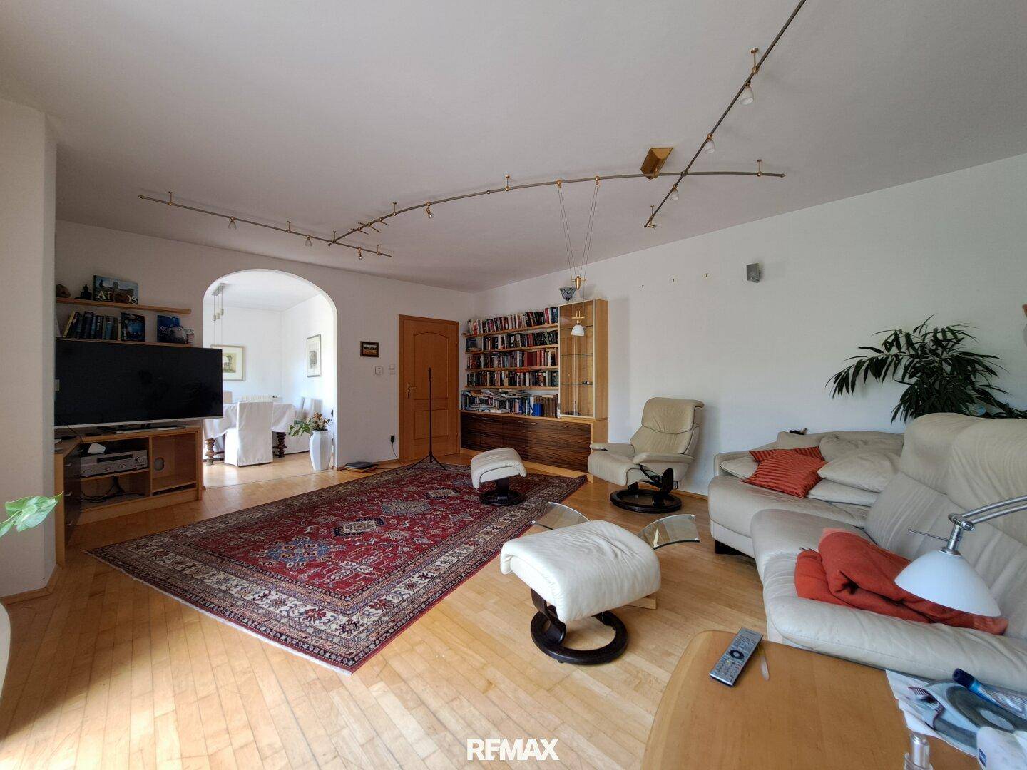 Helles Wohnzimmer mit Parkettboden, bequemen Sofas und einem Bücherregal.