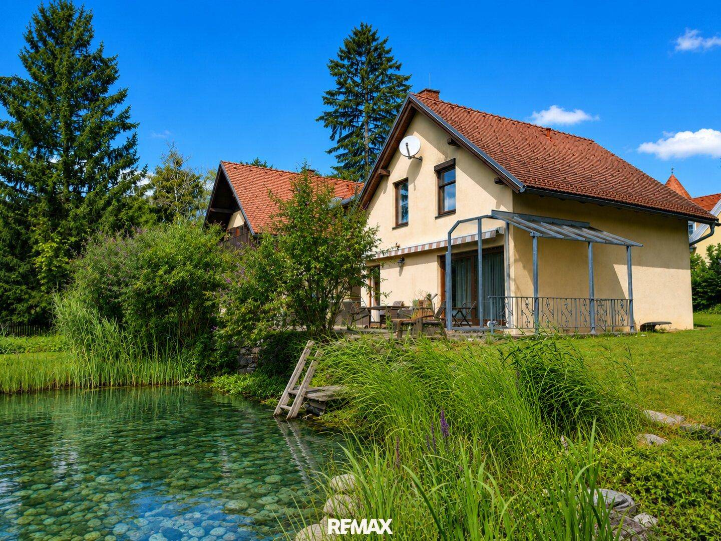 Rückansicht des Hauses mit einem natürlichen Teich und üppiger grüner Vegetation.