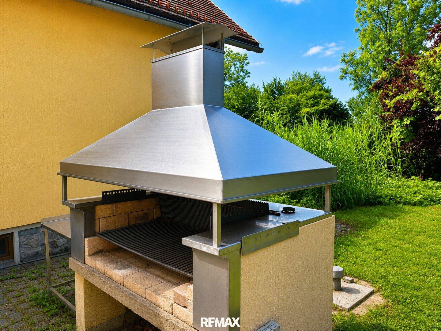 Moderner Edelstahl-Grillplatz im Garten, ideal für sommerliche Zusammenkünfte im Freien.