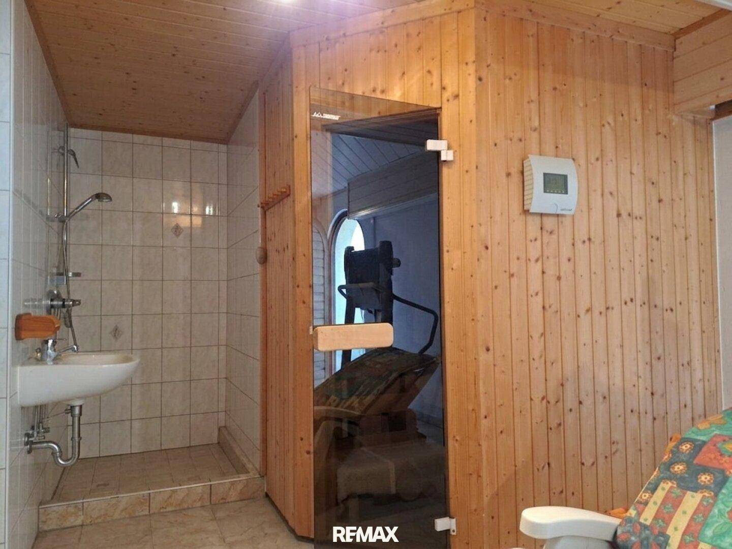Wellnessbereich mit Holzsauna, Dusche und Entspannungsliege.