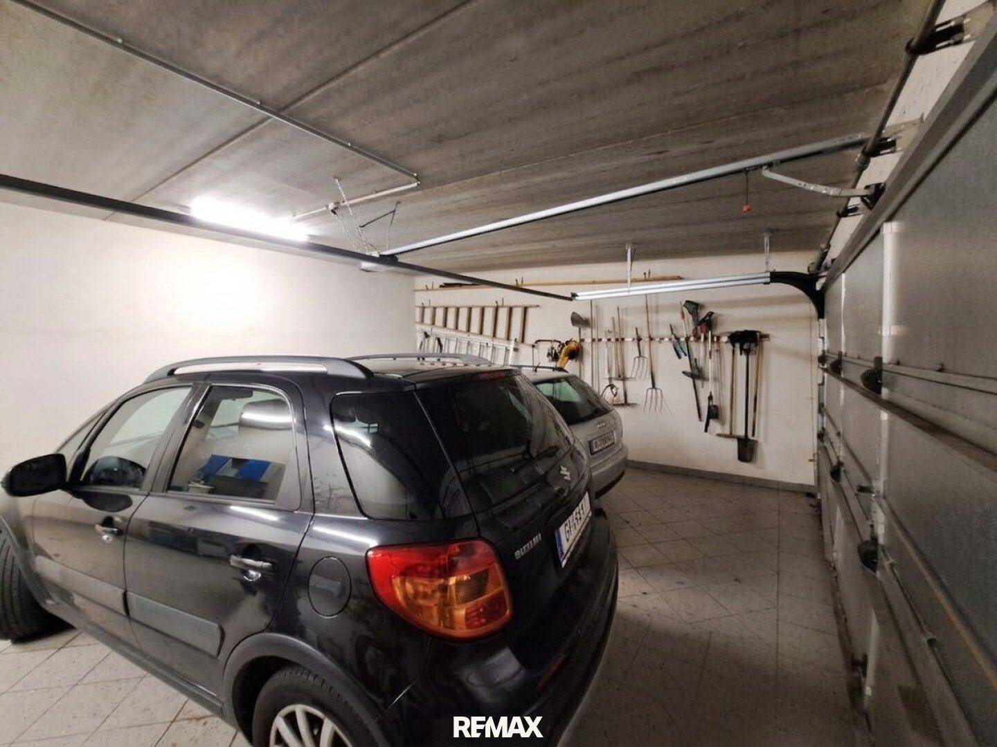 Geräumige Garage mit Platz für zwei Autos und Werkzeugaufbewahrung.