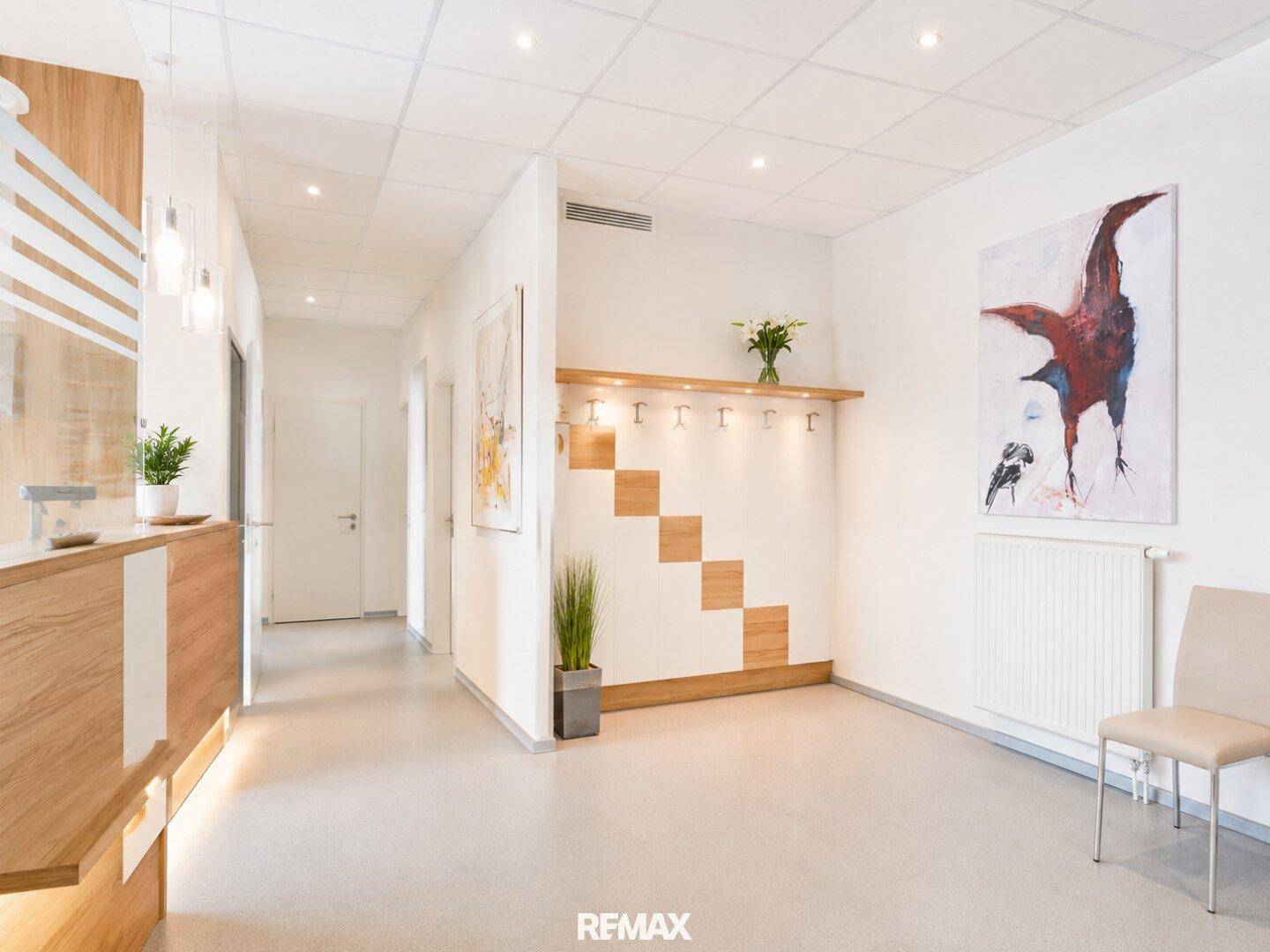 Freundlicher Empfangsbereich mit Kunst an der Wand und heller Garderobe.