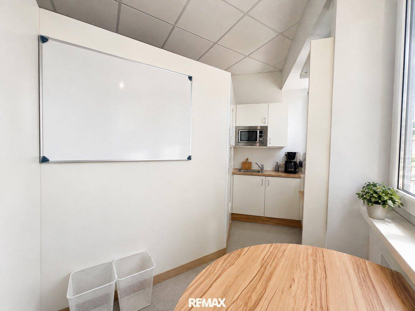Kleiner Pausenraum mit Küchenzeile, Holztisch und Whiteboard an der Wand.