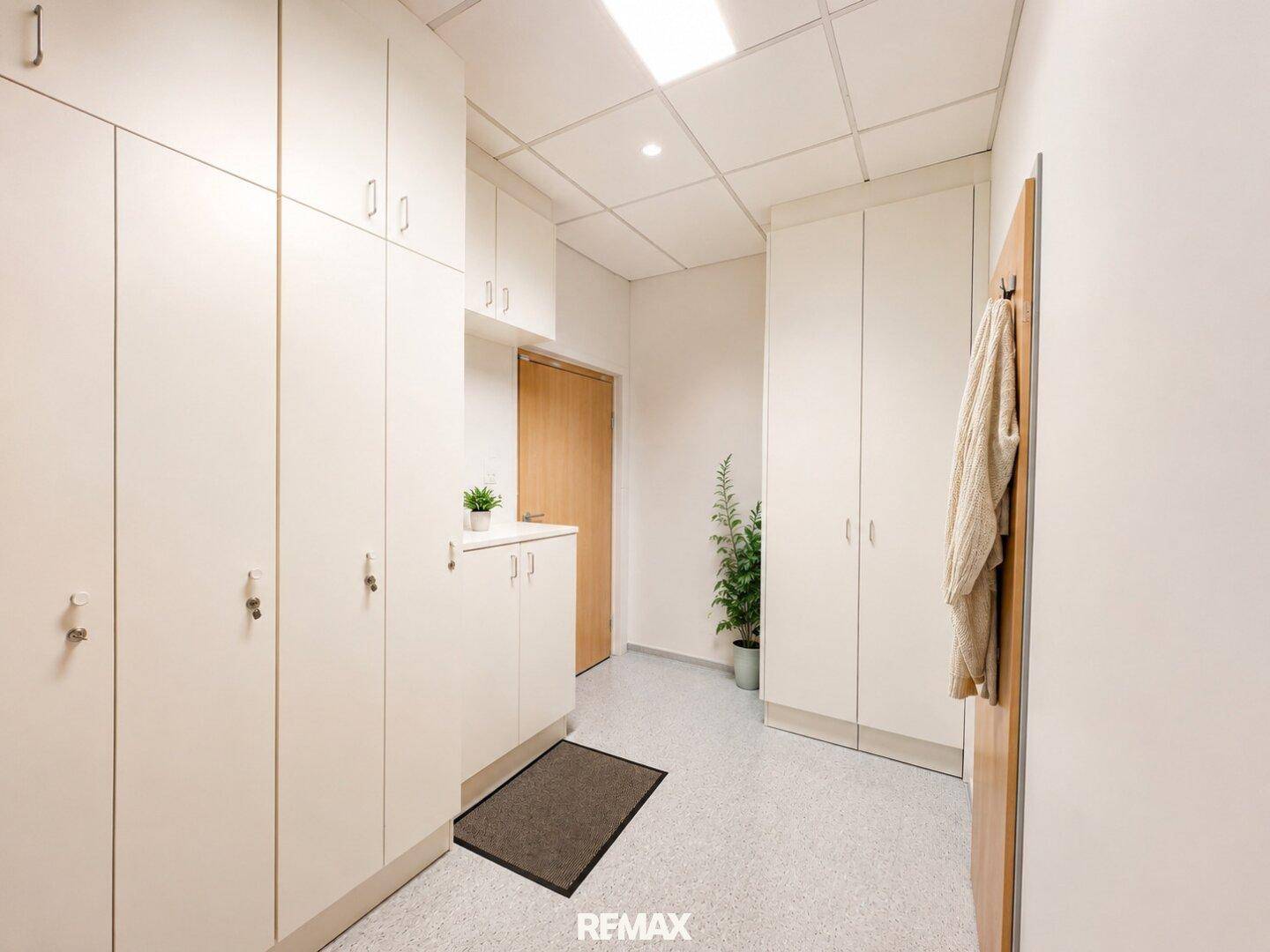 Geräumiger Flur mit vielen weißen Schränken und einem Teppichläufer, ideal für Umkleidebereiche.