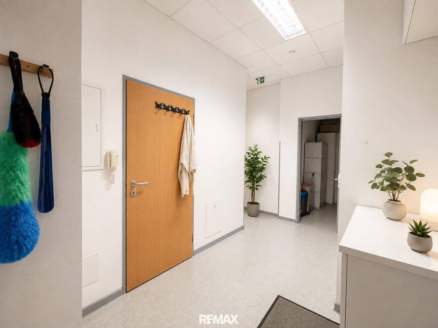 Eingangsbereich mit Garderobe, Gegensprechanlage und hellem Bodenbelag, der zu den Räumen führt.