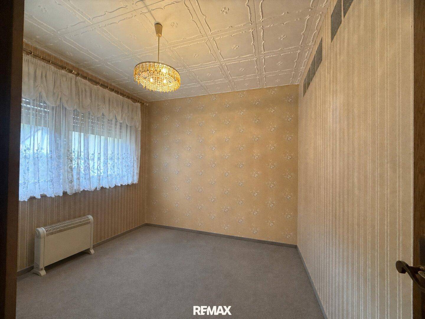 Schlafzimmer mit Teppichboden, gemusterter Tapete und strukturiertem Deckenpaneel.