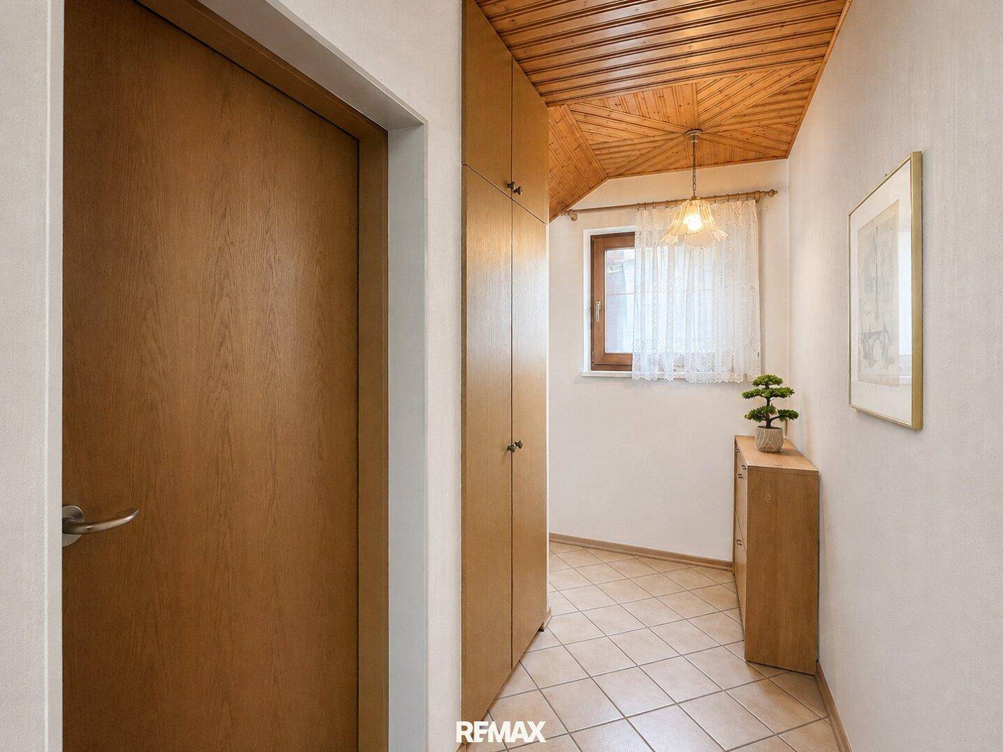 Eingangsbereich mit Fliesenboden, Holzdecke und praktischen Einbauschränken.
