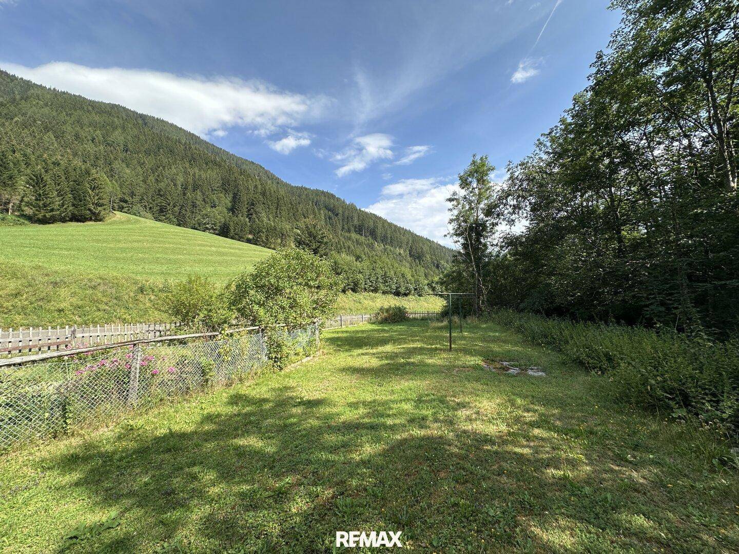 Weitläufiger Gartenbereich mit Rasenfläche und Blick auf die umliegenden grünen Hügel.
