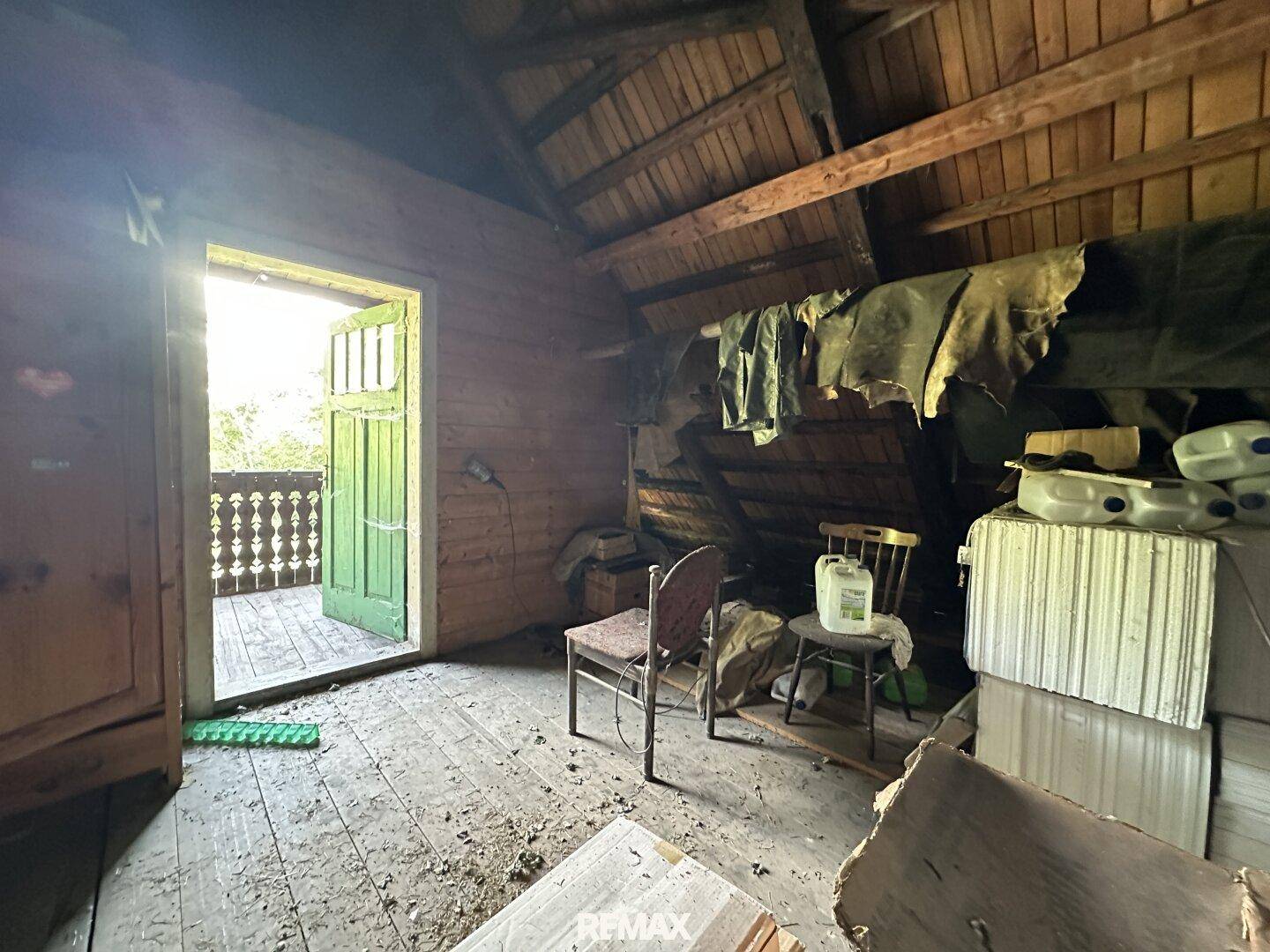 Heller Dachboden mit Holzboden und Zugang zu einem kleinen Balkon.