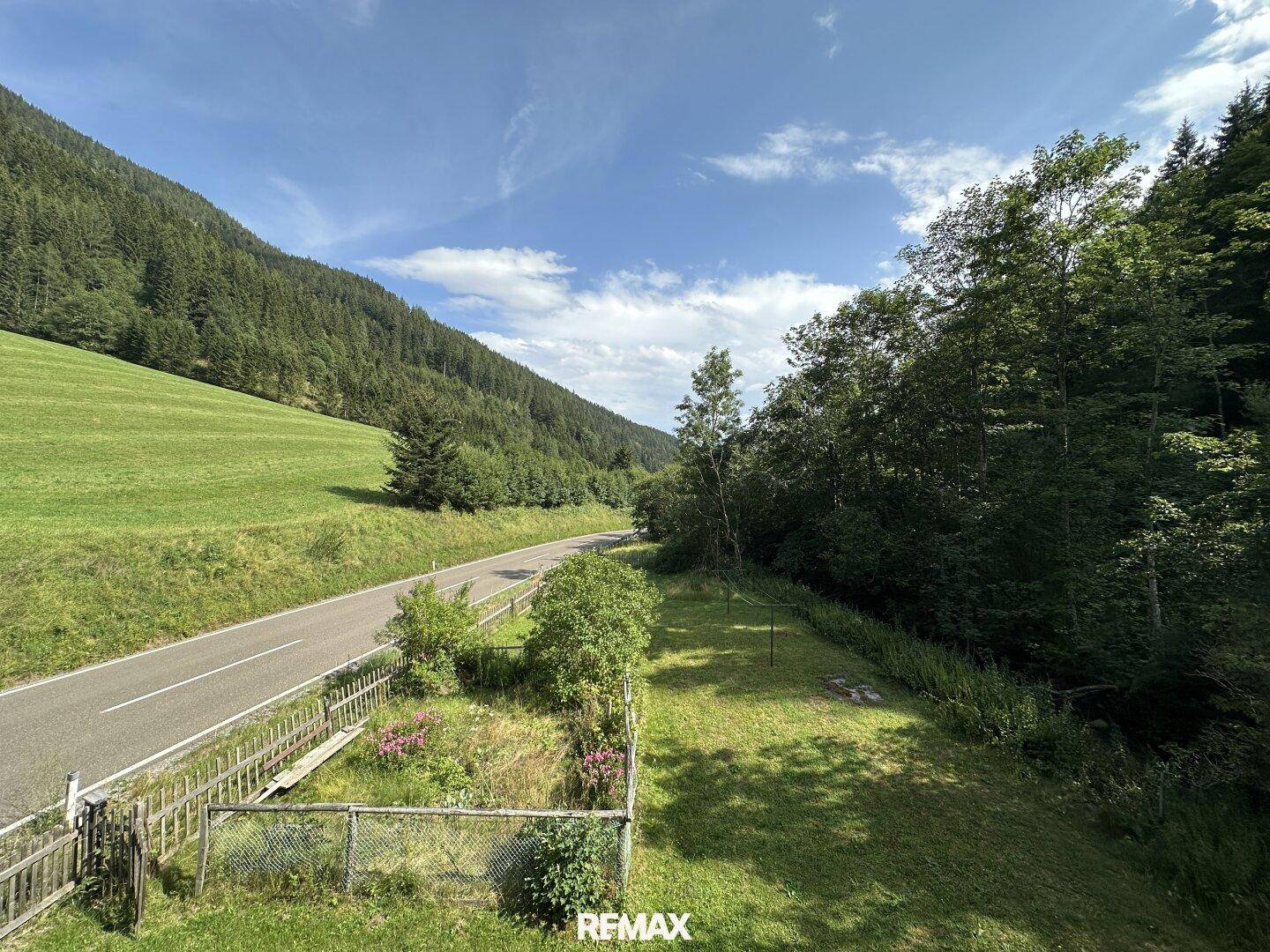 Blick auf die Landstraße und die grüne Landschaft mit bewaldeten Hügeln.