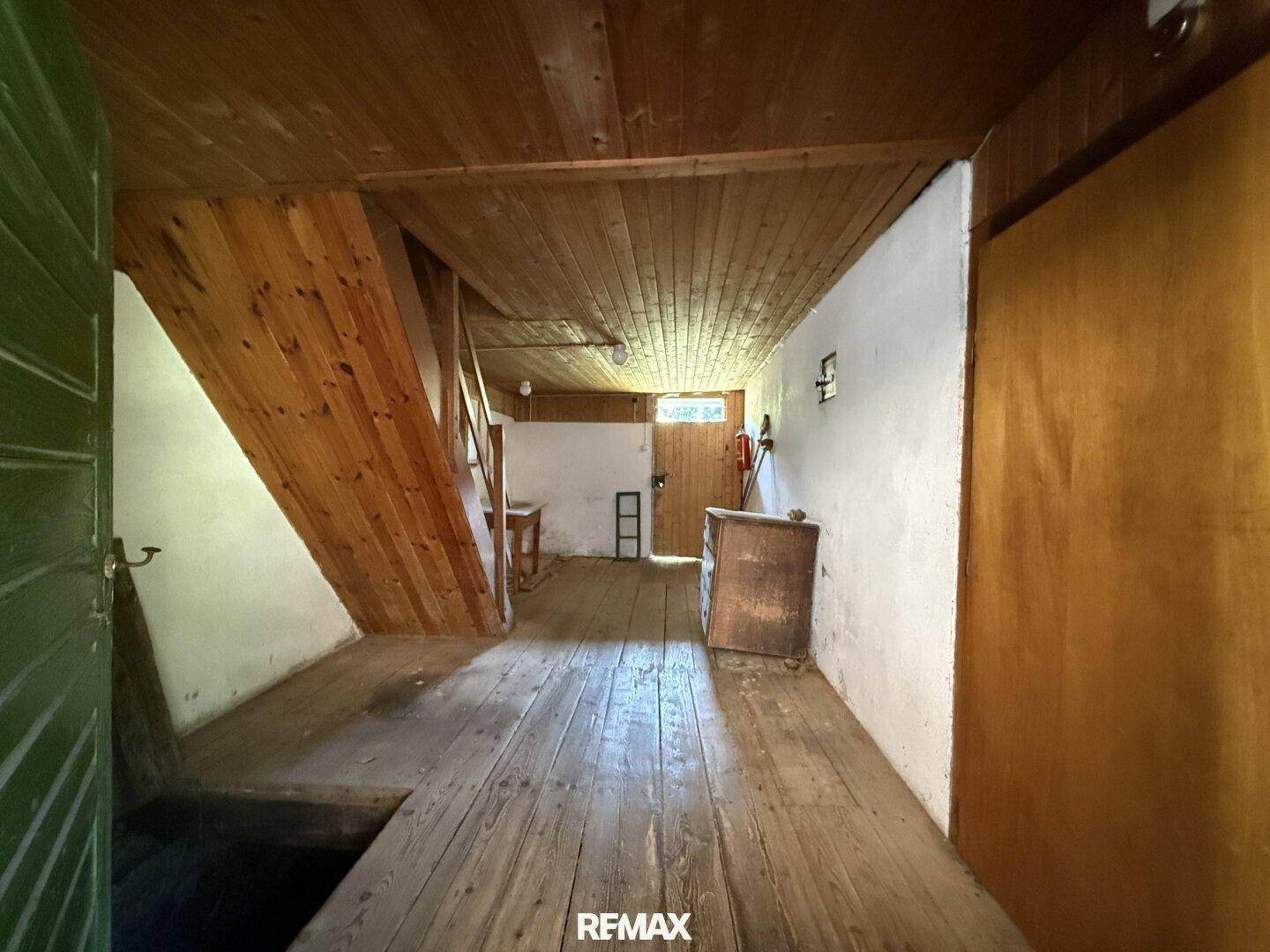 Rustikaler Flur mit Holztreppe und Holzboden, der zu weiteren Räumen im Obergeschoss führt.