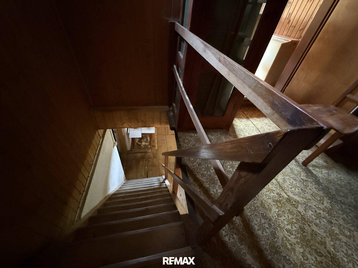 Holztreppe mit Geländer führt in die unteren Etagen, rustikaler Stil und Holzelemente.
