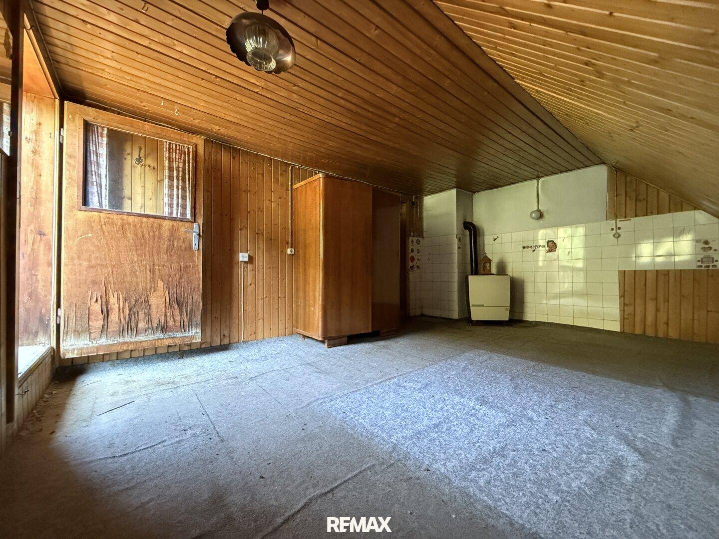 Unausgebauter Raum im Dachgeschoss mit Fliesenwand und Holzdecke, vielseitig nutzbar.