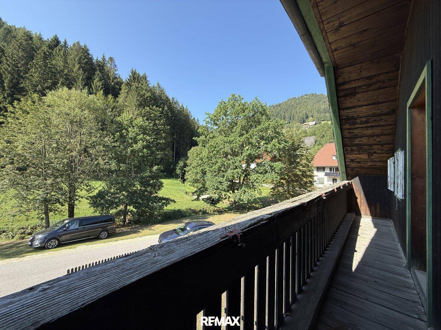 Langer Holzbalkon mit rustikalem Geländer und weitem Blick auf die umliegende Natur.