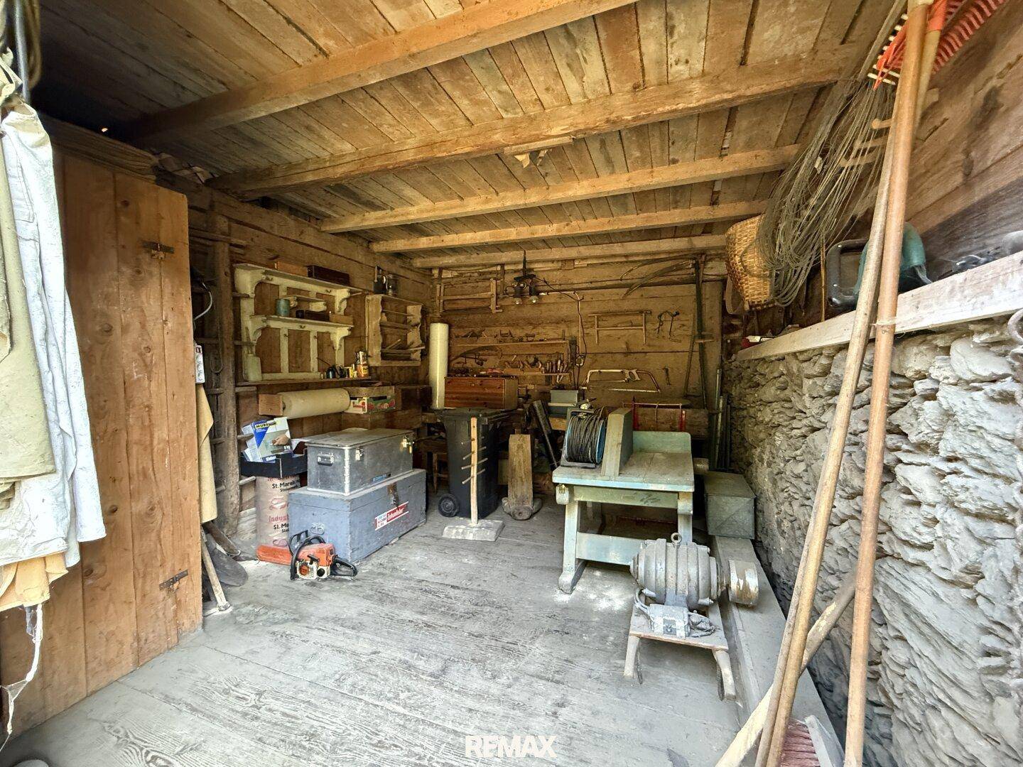 Werkstattbereich in einer Holzscheune mit verschiedenen Werkzeugen und Arbeitsgeräten.