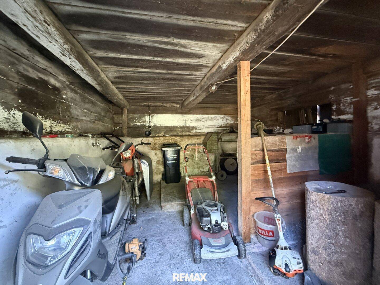 Garage oder Abstellraum mit Motorrollern, Rasenmähern und Gartengeräten, praktisch und geräumig.
