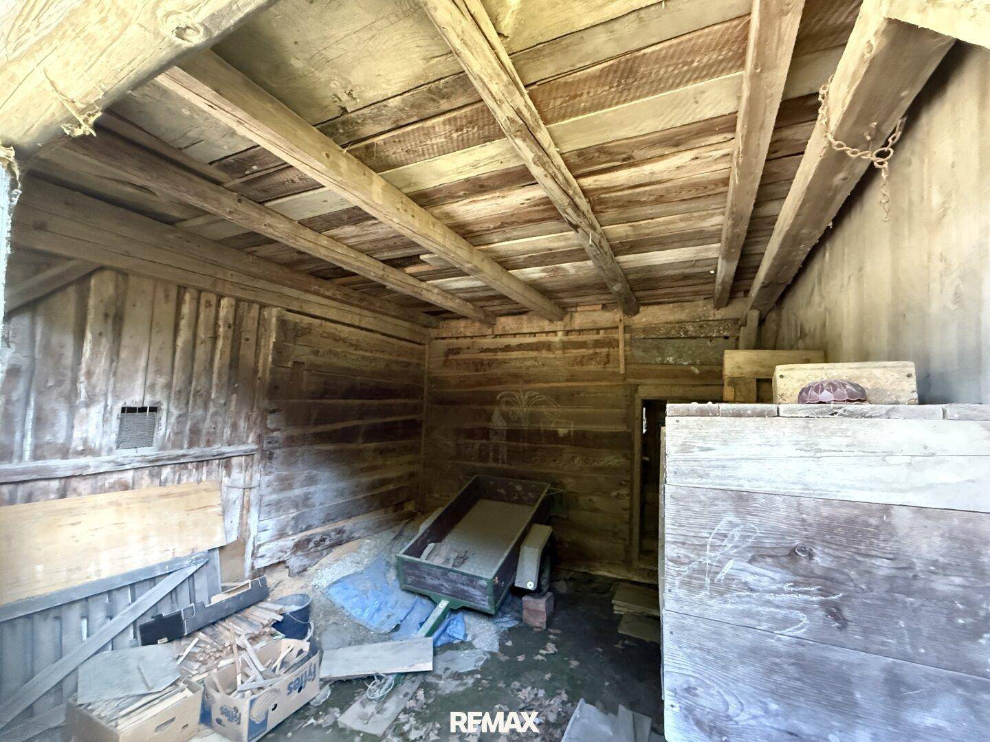 Obergeschoss einer Holzscheune mit Holzwänden und -decke, dient als Lagerfläche.