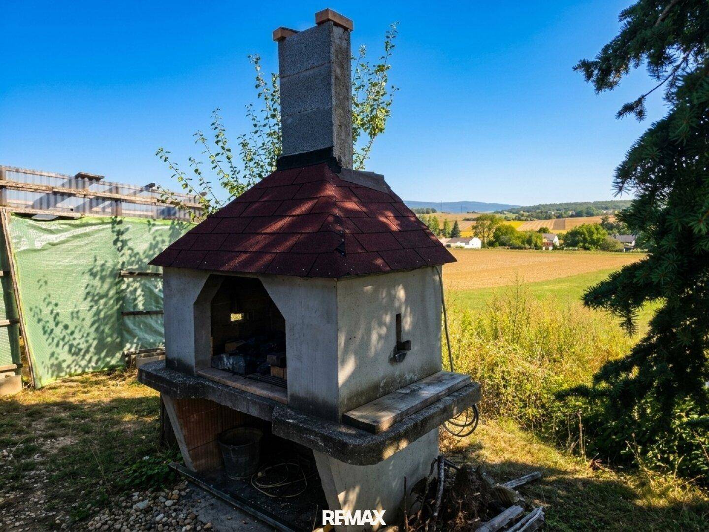 Gemauerter Außenofen mit Schornstein in ländlicher Umgebung, ideal für Grillabende.