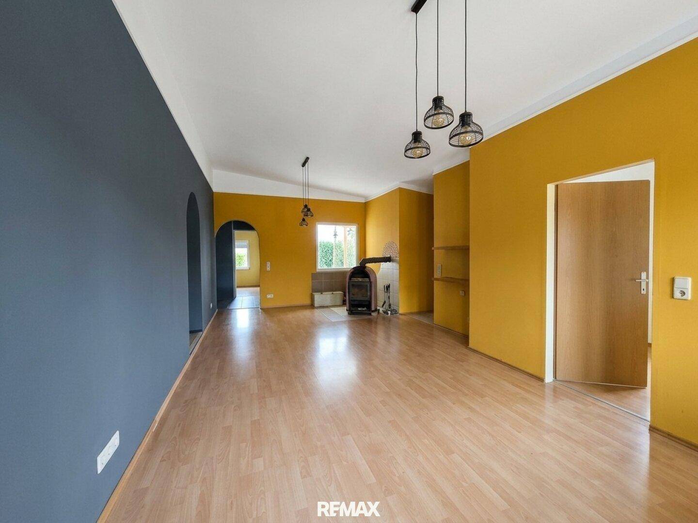 Helles Wohnzimmer mit Holzboden, farbigen Wänden und Blick auf den Garten.