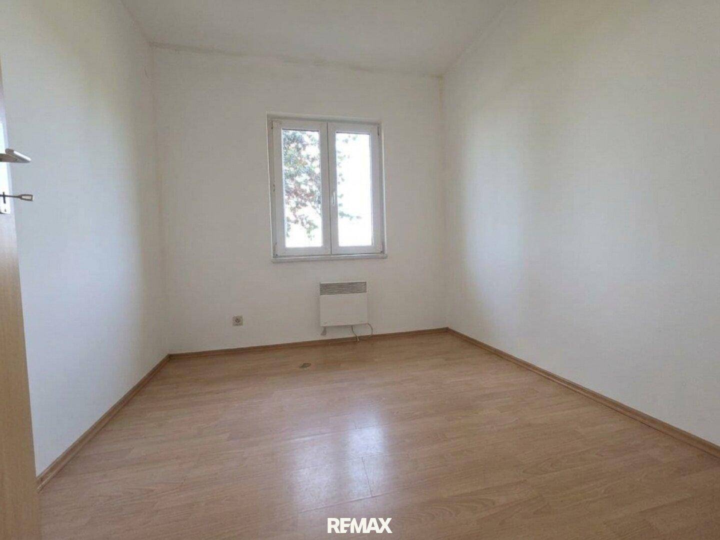 Helles Schlafzimmer mit Laminatboden und weiß gestrichenen Wänden, bereit zur individuellen Gestaltung.
