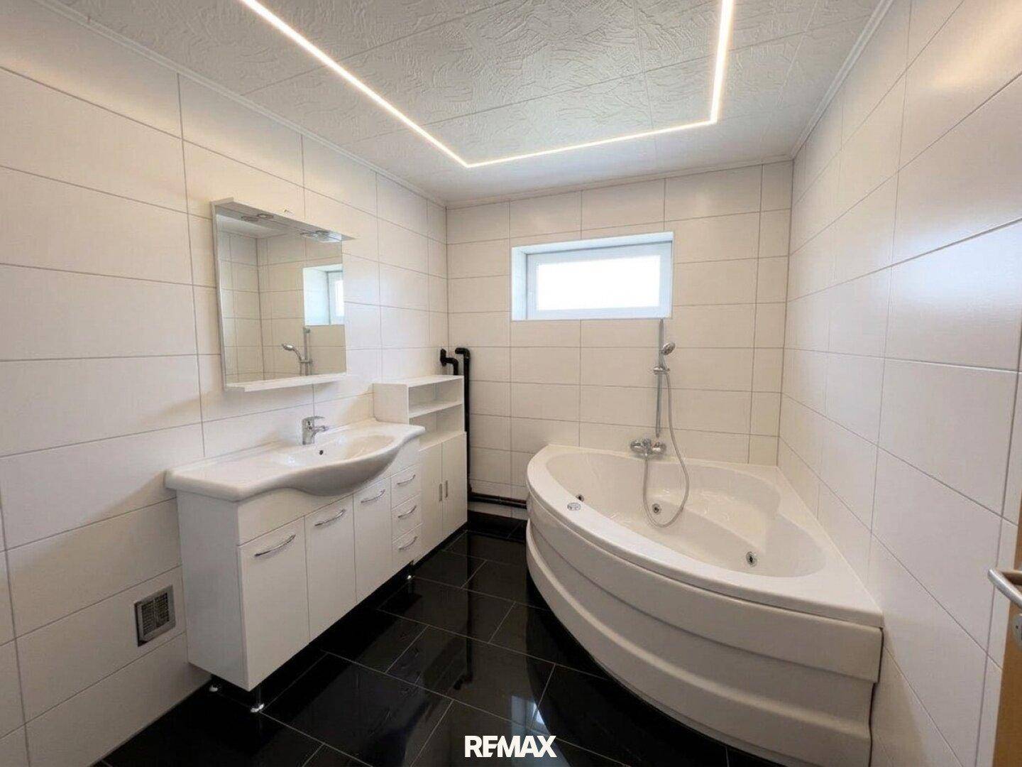 Modernes Badezimmer mit Eckbadewanne, weißen Fliesen und integrierter Beleuchtung.