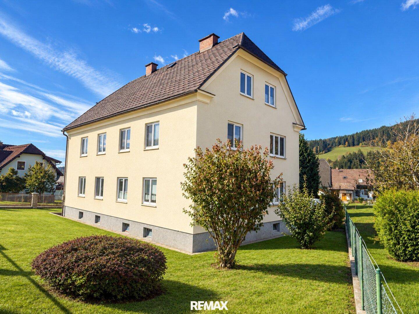 Gepflegtes Einfamilienhaus mit weitläufigem Rasen und klarem Himmel.