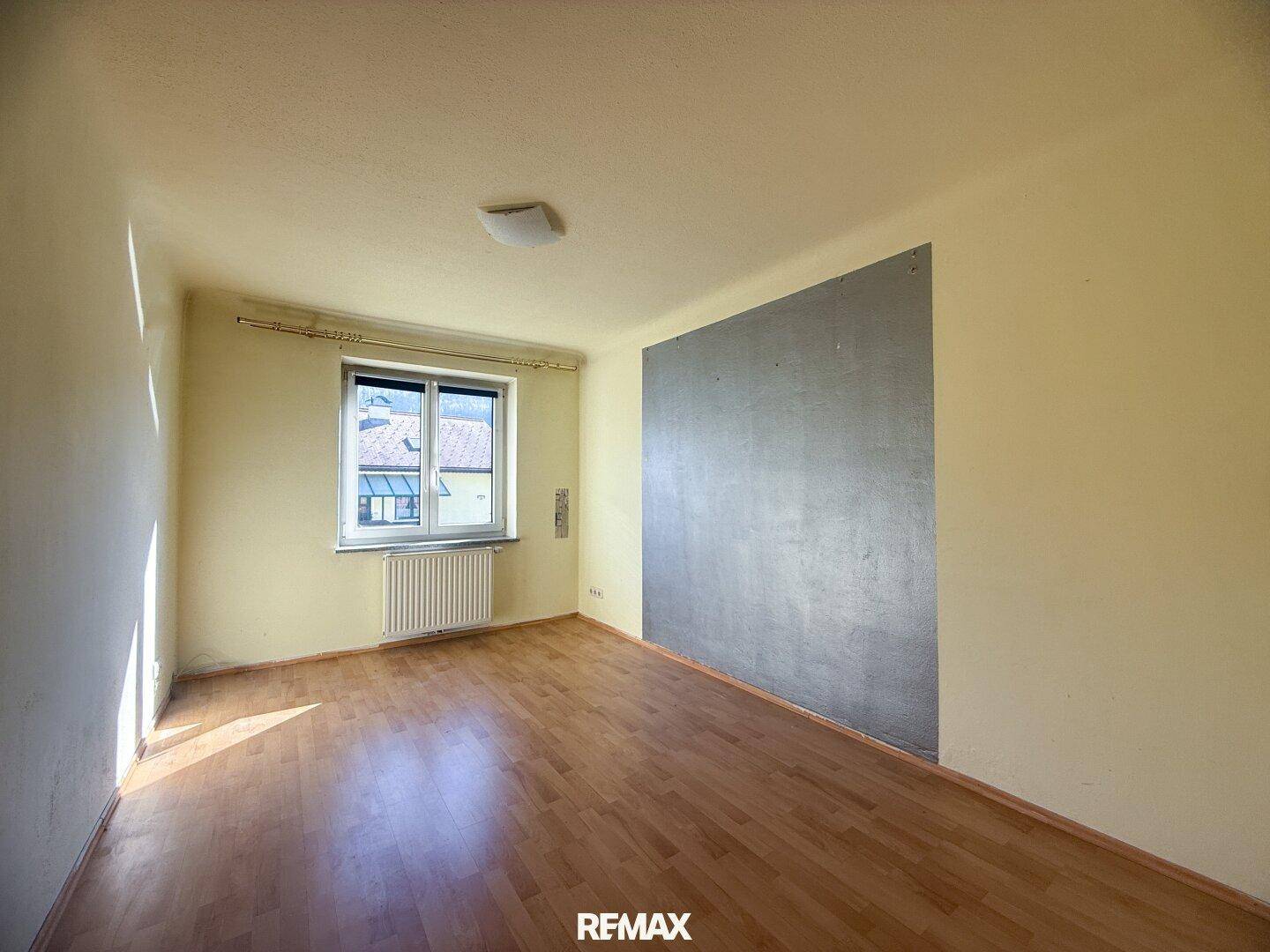 Helles Zimmer mit Holzboden und gelben Wänden, ideal als Schlaf- oder Arbeitszimmer.
