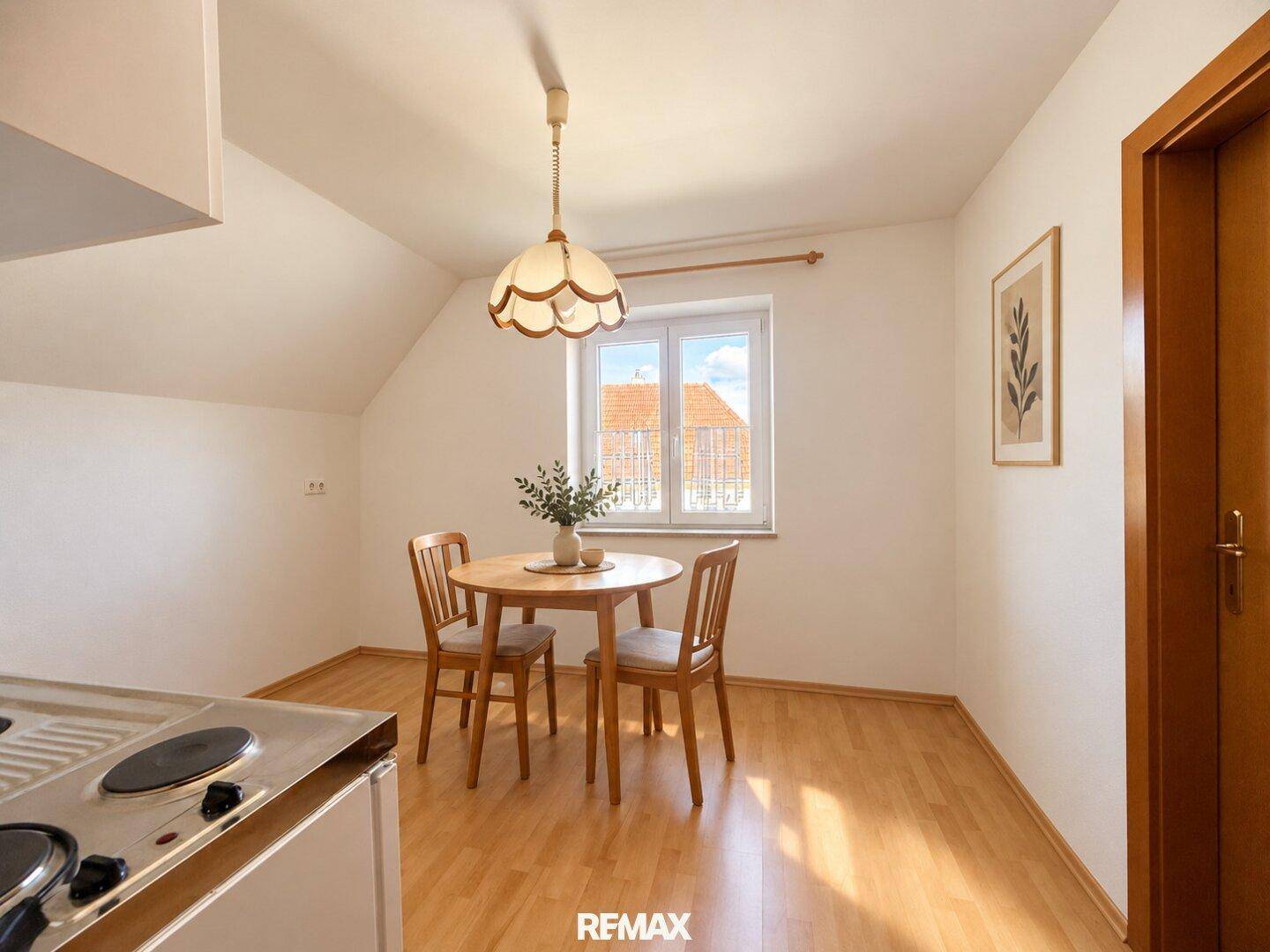 Helle Dachgeschossküche mit Essbereich, Holzboden und modernem Esstisch.