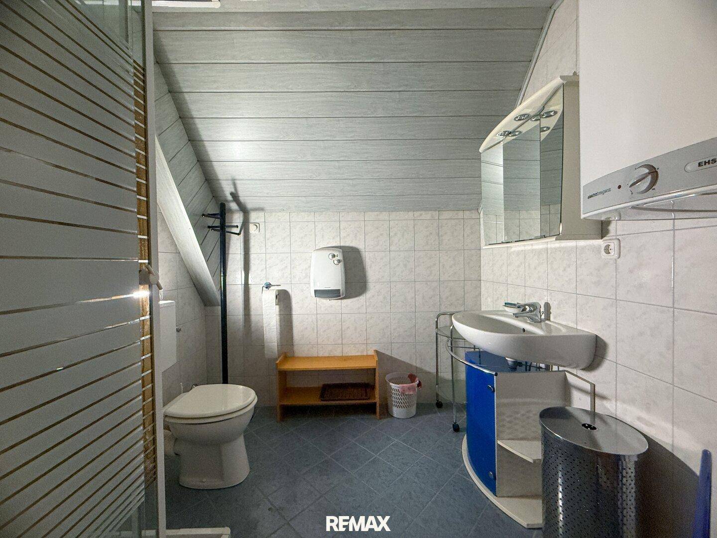 Dachgeschoss-Badezimmer mit Dusche, WC und Waschbecken unter schräger Decke.
