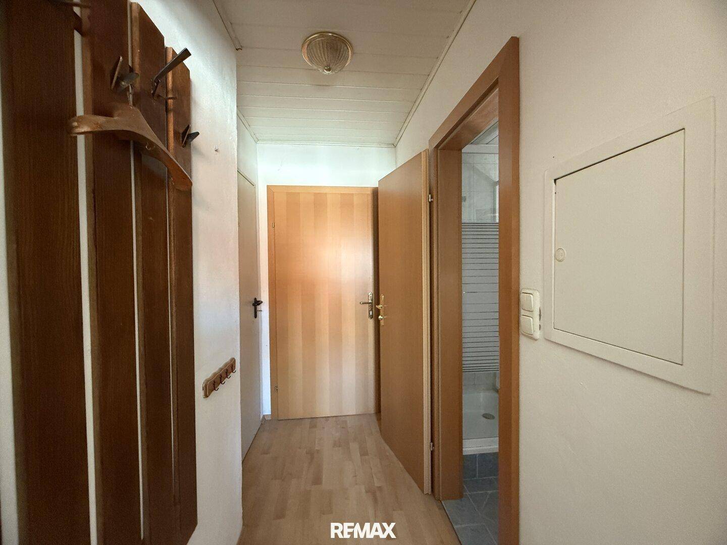 Schmaler Flur mit Garderobe und Holztüren, der zu den Zimmern führt.