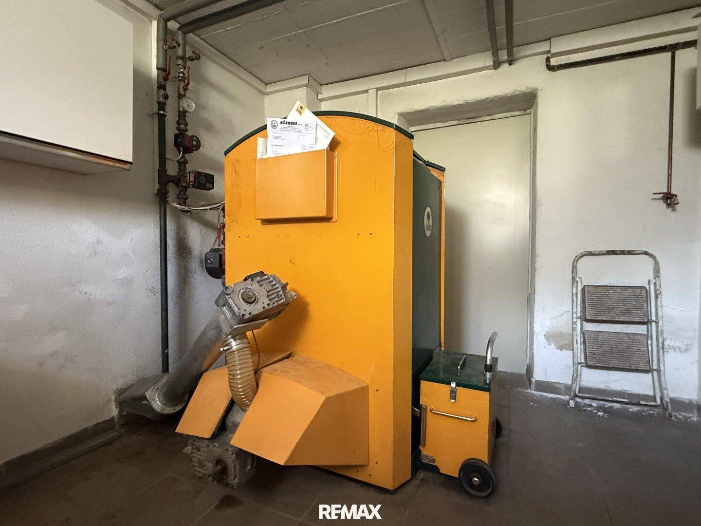Heizraum im Keller mit großem gelben Heizkessel und technischen Installationen.