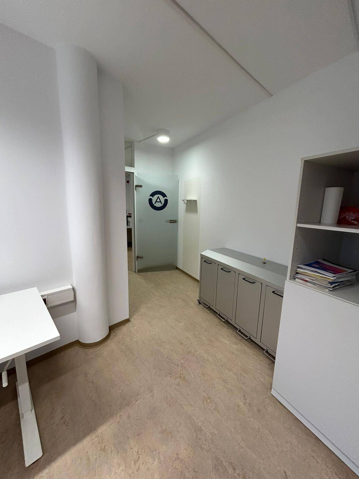 Heller Flur mit modernem Bodenbelag und einem praktischen Sideboard, der zu einem weiteren Büroraum führt.