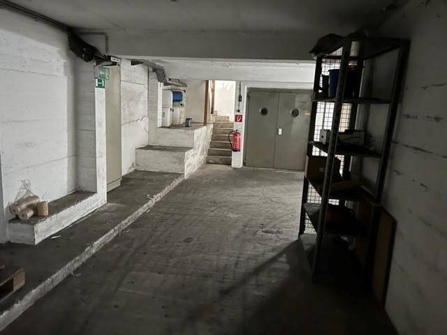 Kellerraum mit Betonboden, Lagerregalen und Treppenaufgang, funktional und geräumig.