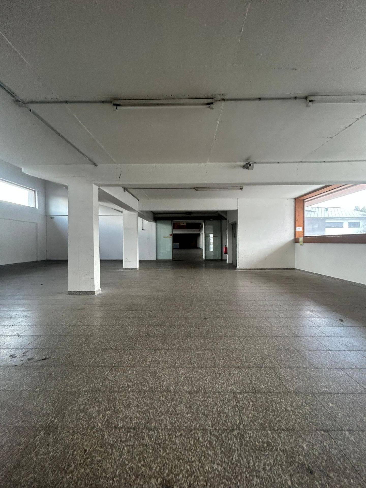 Heller, offener Gewerberaum mit Säulen, Terrazzoboden und natürlichem Lichteinfall.