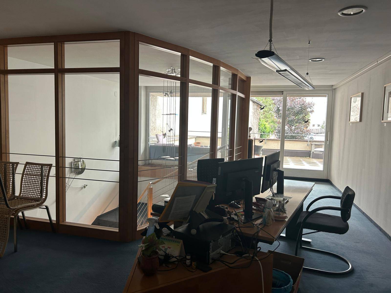 Büro mit Schreibtischen, Computermonitoren und einer großen Glasfront mit Blick nach draußen.