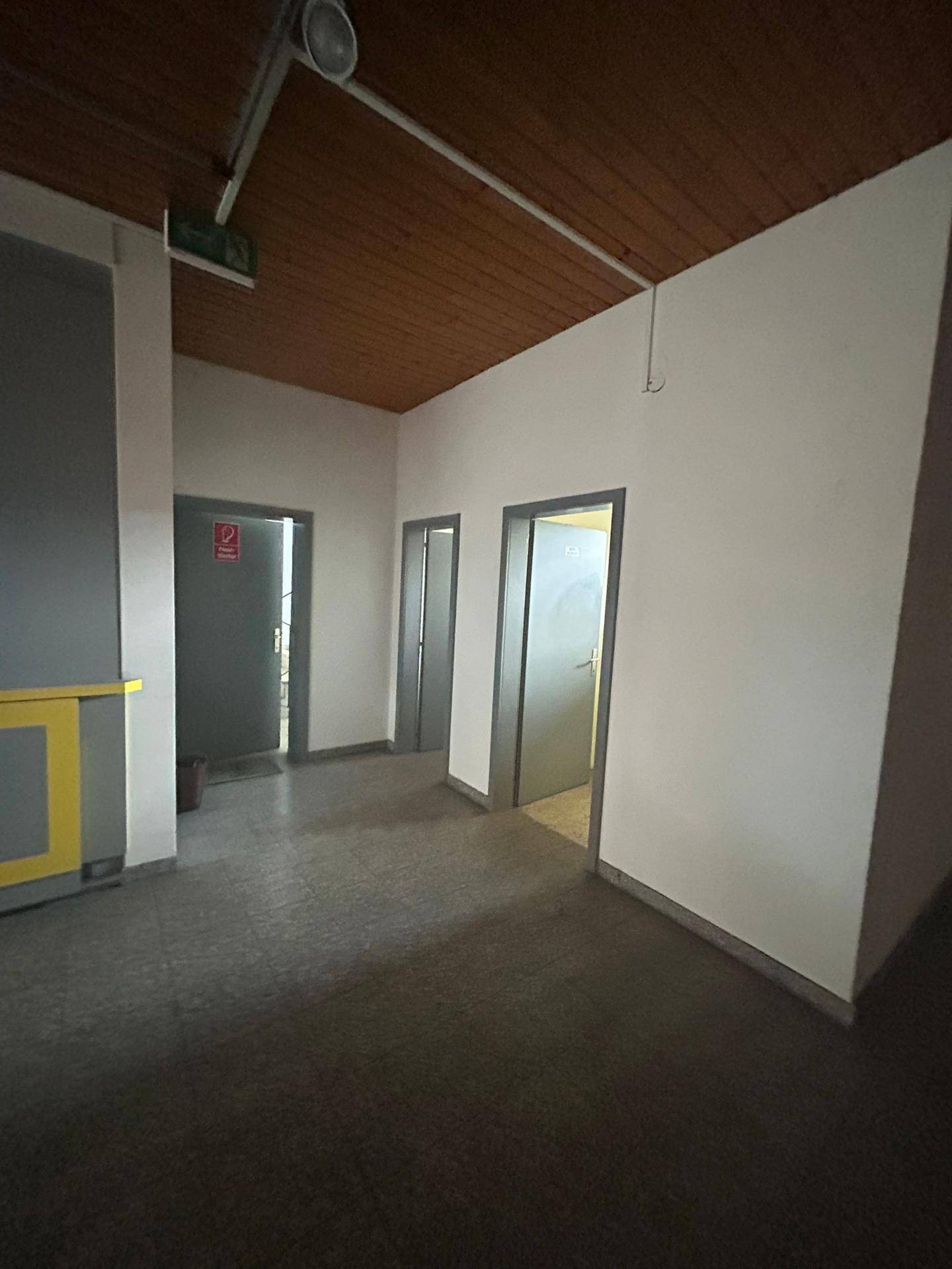 Flur mit Holzboden und mehreren Türen, der zu verschiedenen Räumen führt.